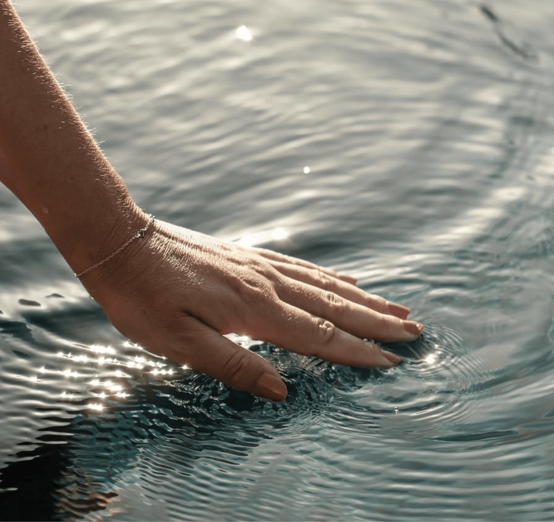 Hand streicht über das Wasser im Pool